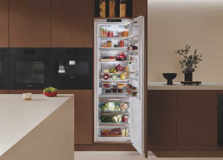 Großer geöffneter Einbaukühlschrank mit Lebensmitteln, mehreren Ablagen und Frischeschubladen in einer modernen Küche mit braunen Fronten.