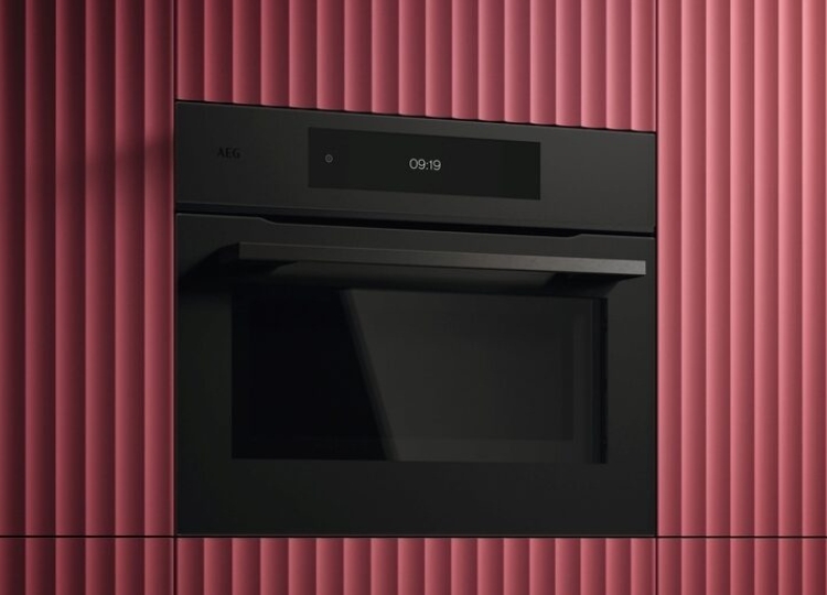 Schwarzer AEG Einbaubackofen mit digitalem Display, integriert in eine Küchenwand mit rot geriffelter Oberfläche.